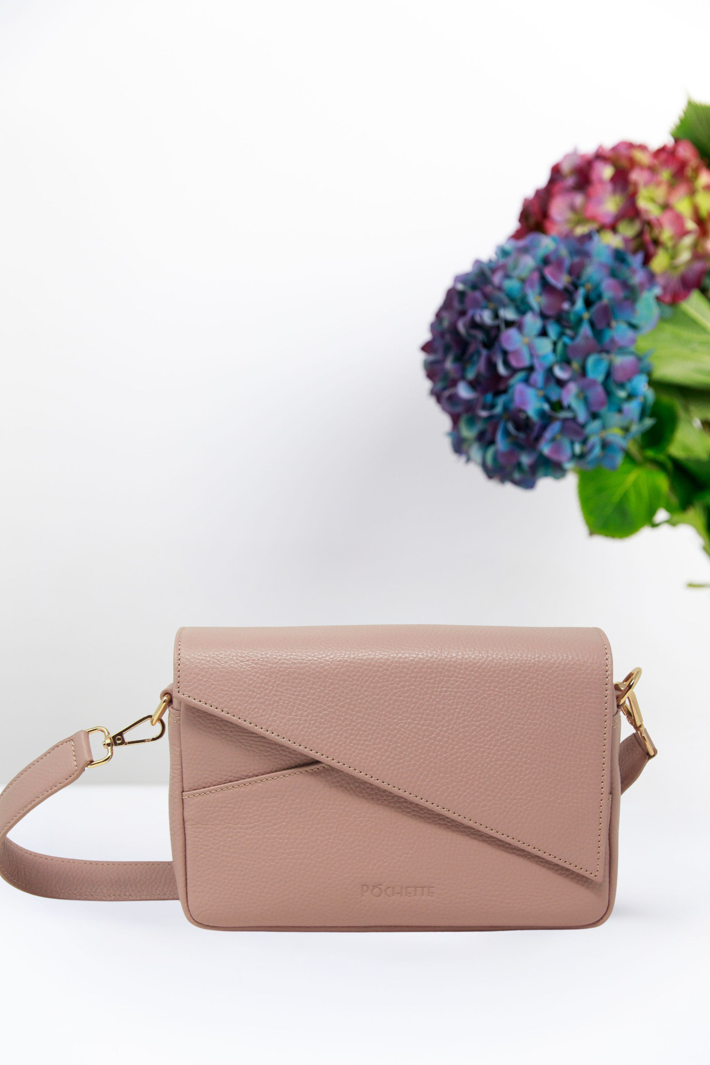 Pink handbag with a white background and flowers in the corner