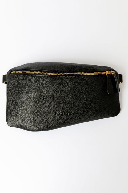 A black swing crossbody bag, called the Póca, on a white surface.