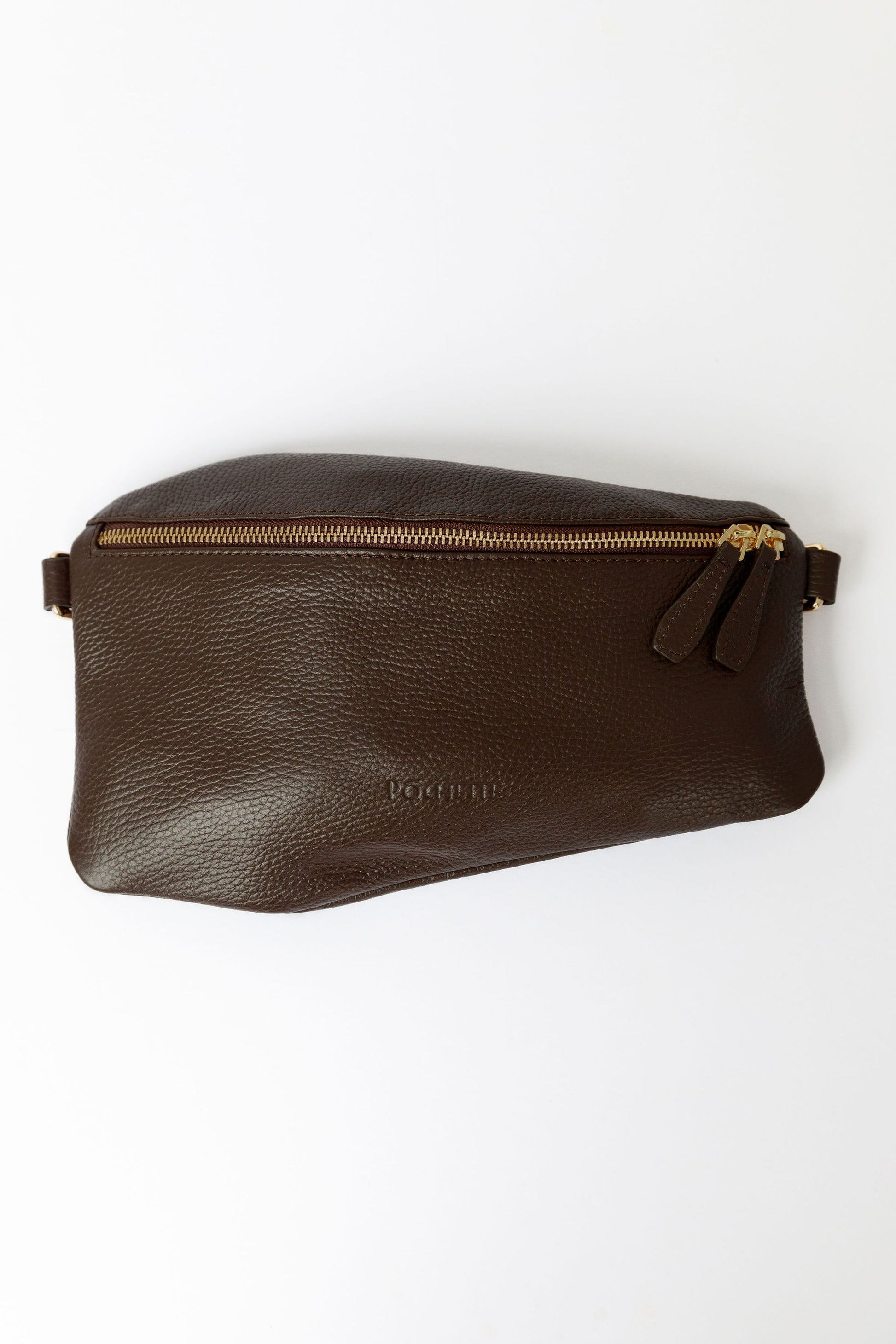 A chocolate brown swing crossbody bag, called the Póca, on a white surface.