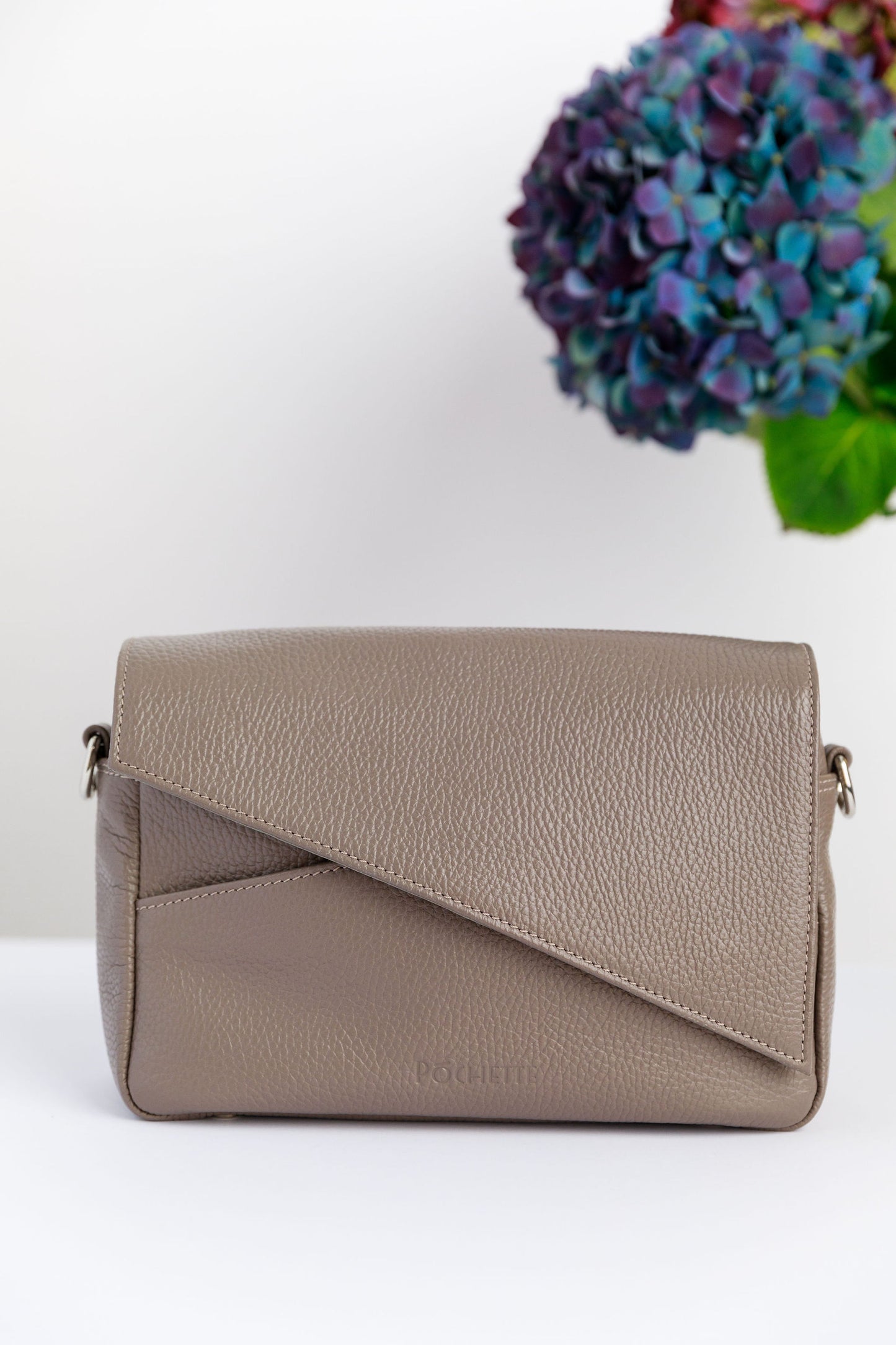 A pottery clay leather flap on a white surface with a blurred hydrangea in the background.