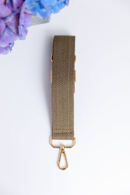 A chocolate brown woven strap on a white surface with a blurred hydrangea in the foreground.