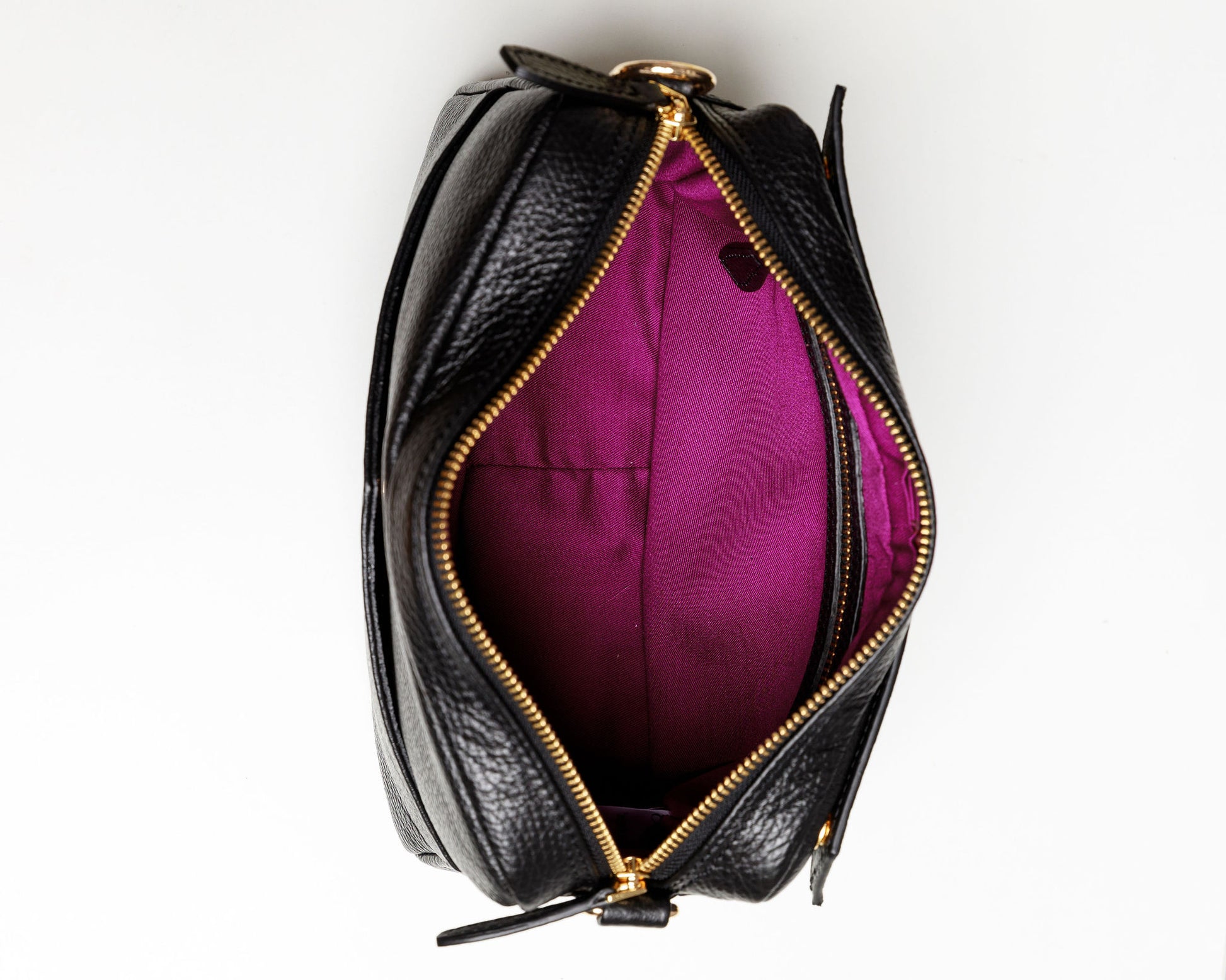 The inside of a black crossbody bag showing the brightly coloured syrah lining and an interior zipped pocket. 