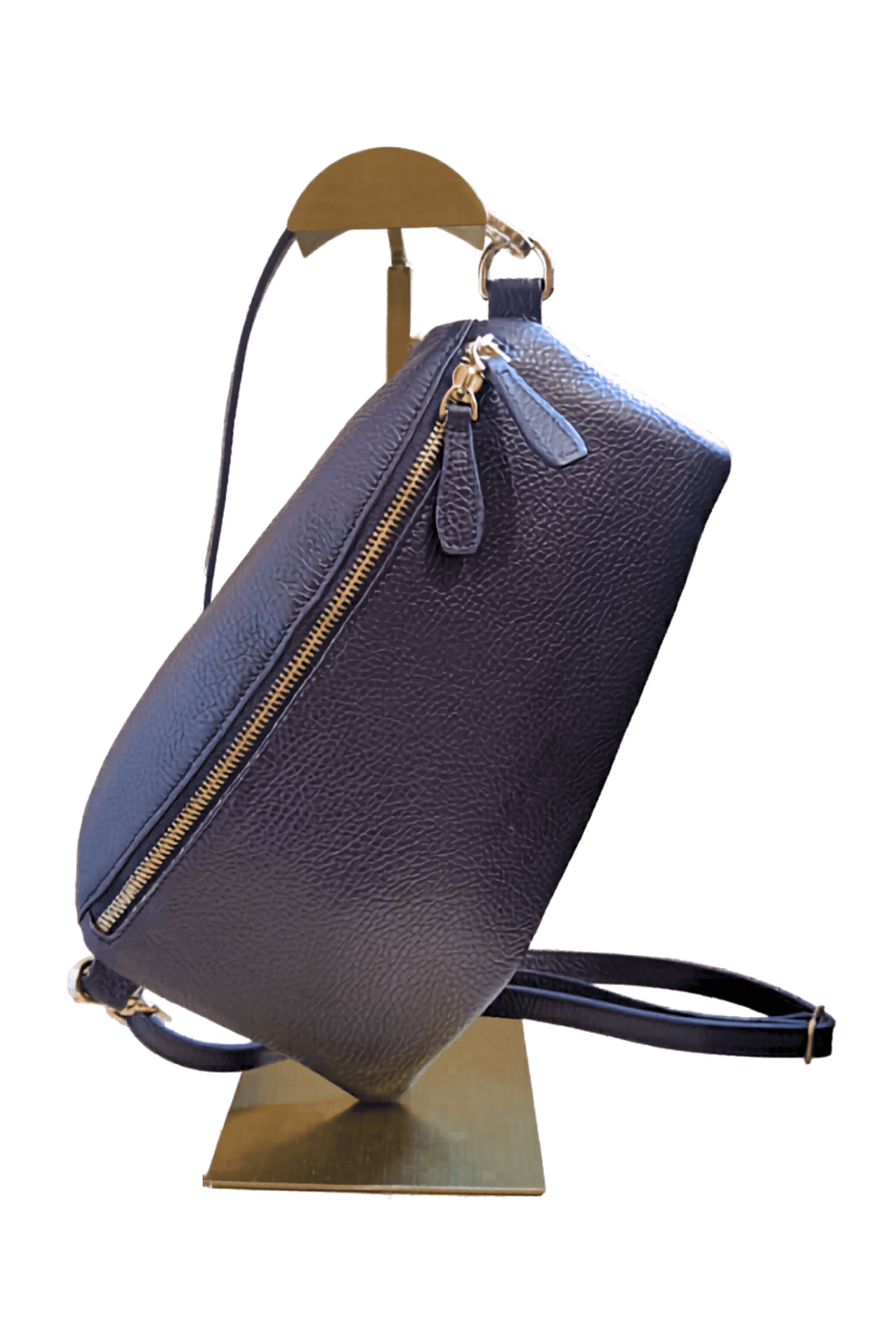 Navy leather handbag on a gold stand against a white background