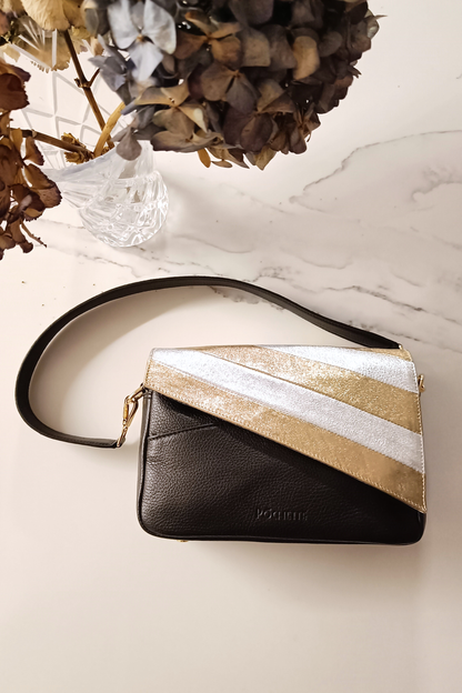 Gold and silver striped leather cover on a black Póchette Danu handbag on a marble surface
