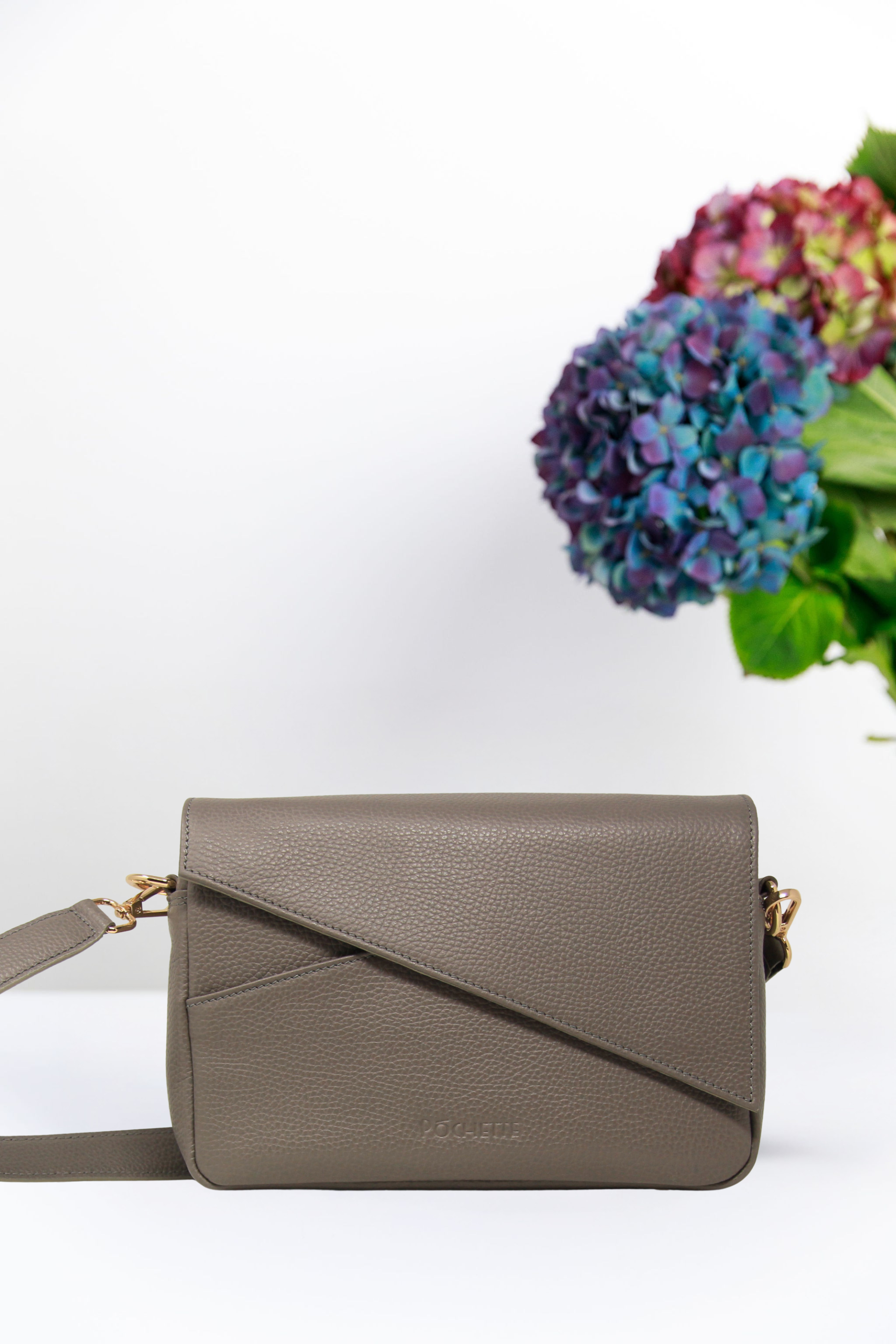A grey handbag with flowers in the background