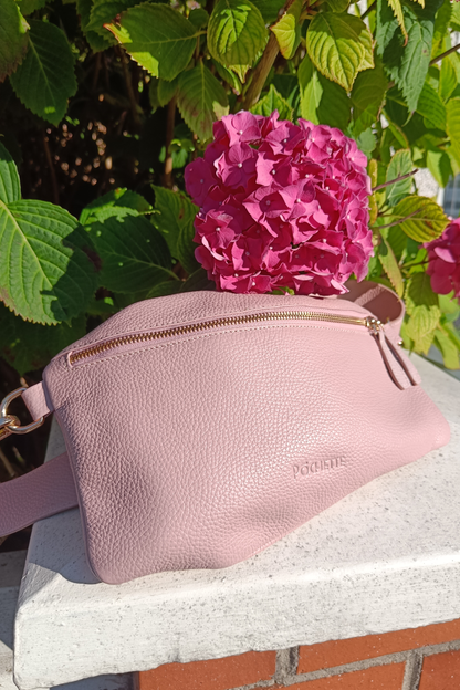 Powder Pink Póca handbag on a sunny day with a bright pink hydrangea beside it