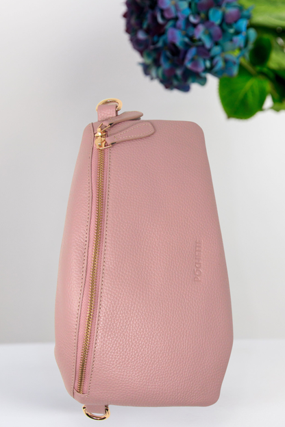 Pink leather handbag with gold zipper on a white background