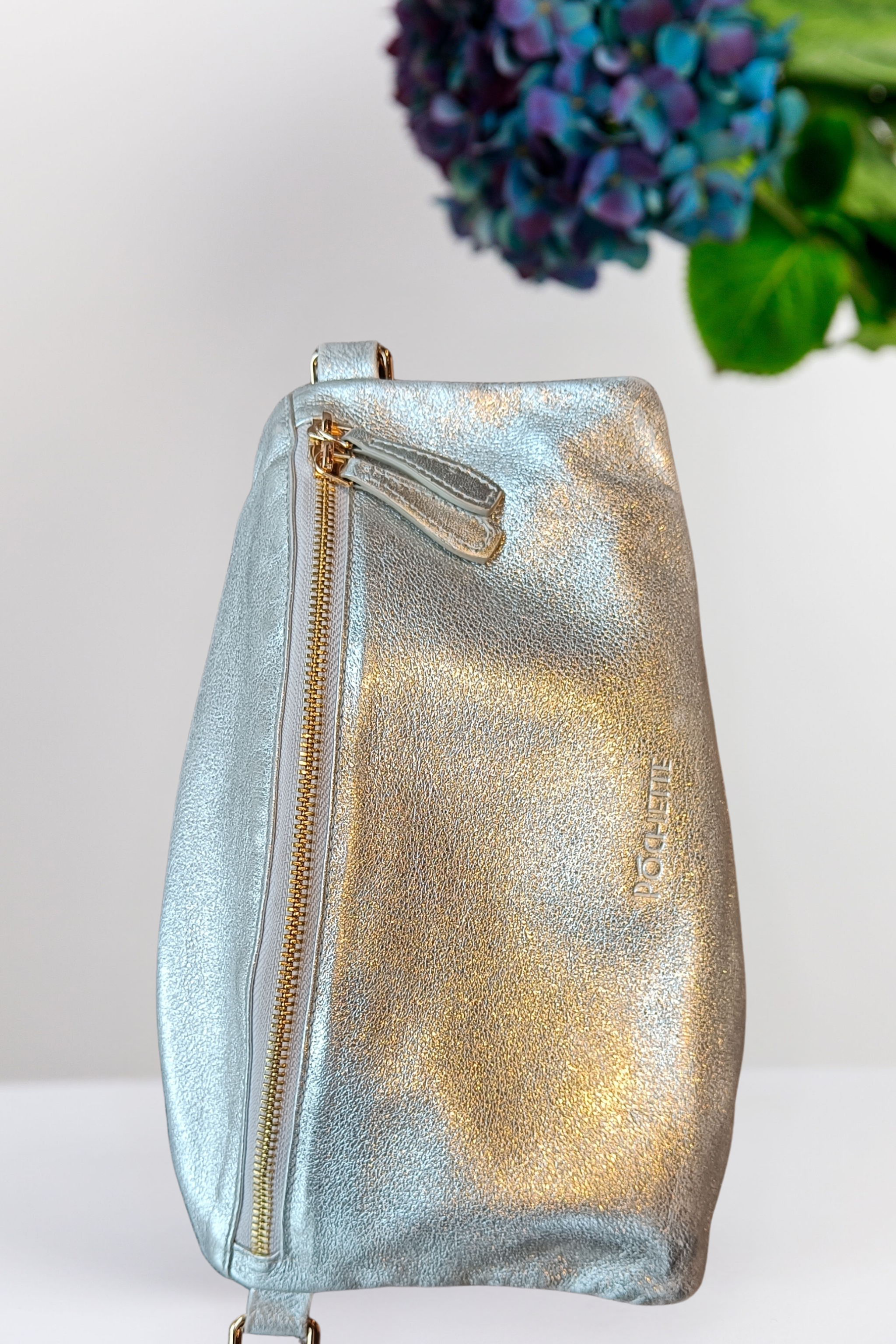 Silver glittery handbag with a gold zipper on a white background