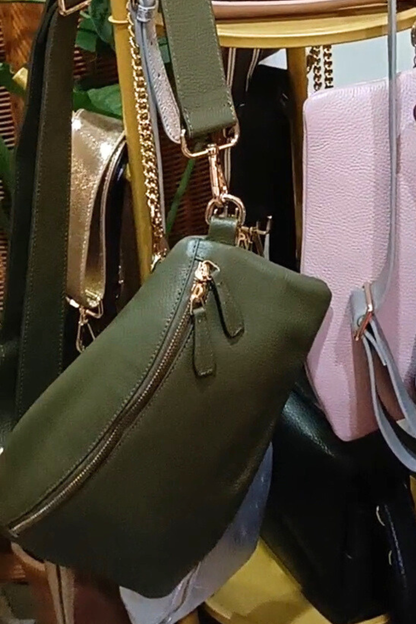 Green handbag with gold zipper and handle among other bags.