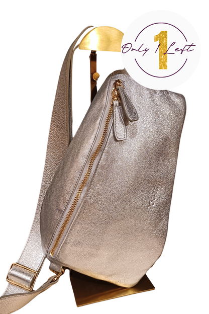 A metallic silver handag with gold-tone zippers, displayed on a gold stand against a white background. A white circular badge in the top right corner features a gold '1' and the text 'Only 1 Left'.