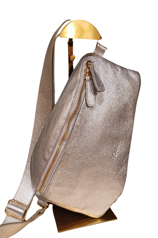 A metallic silver handbag with gold hardware, displayed on a gold-colored stand.